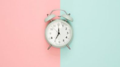 A white alarm clock on a split pink and blue backdrop