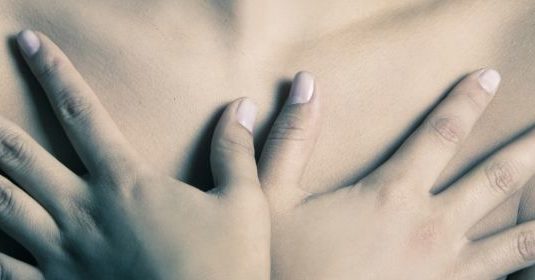 A woman with her hands covering her bare chest