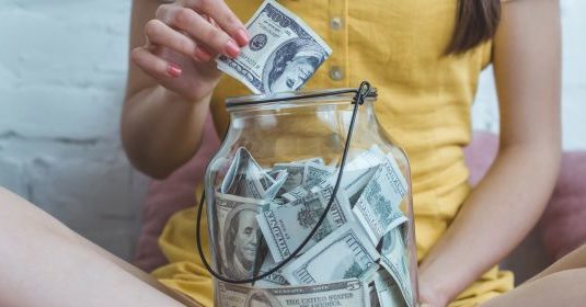 A woman saving money in a jar