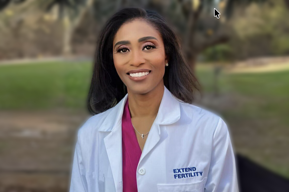 A professional headshot of Dr. Nataki Douglas of Extend Fertility wearing a white Extend Fertility lab coat in an outdoor background