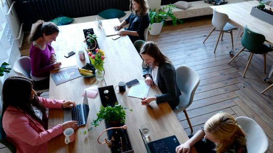 A group of women working together at a table in a coworking space